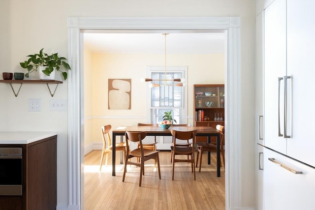 dining space featuring a chandelier, light wood-type flooring, and baseboards