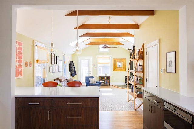 kitchen featuring light countertops, vaulted ceiling with beams, a peninsula, and dark brown cabinets