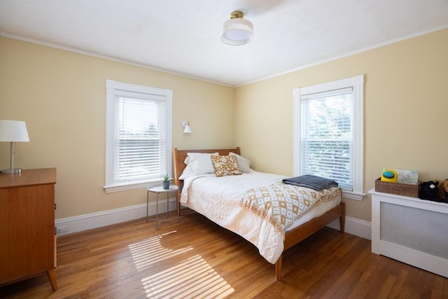 bedroom featuring crown molding, wood finished floors, and baseboards