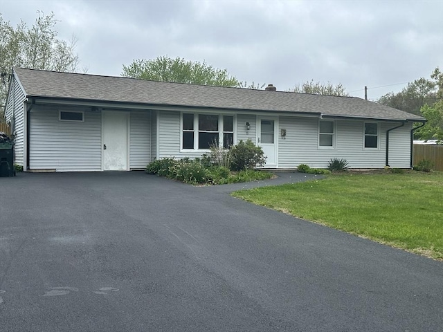 ranch-style home with a front lawn, a shingled roof, and asphalt driveway