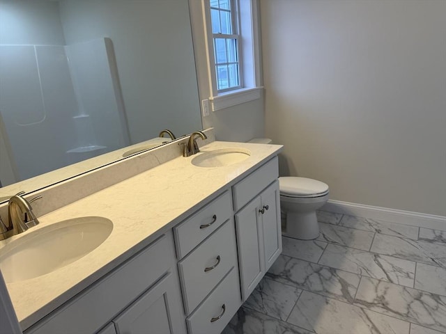 bathroom featuring toilet, marble finish floor, baseboards, and a sink