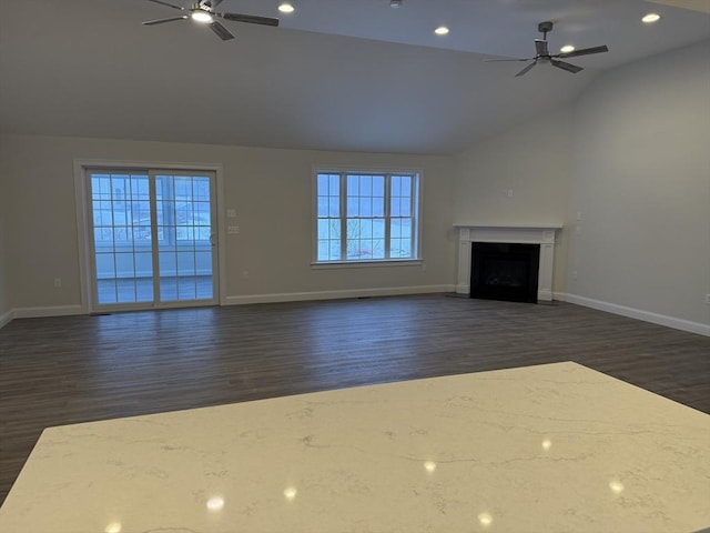 unfurnished living room featuring lofted ceiling, a fireplace with flush hearth, baseboards, and a ceiling fan