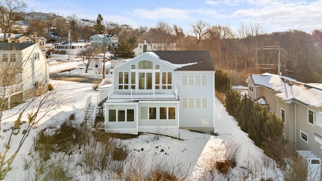 snow covered back of property featuring a balcony