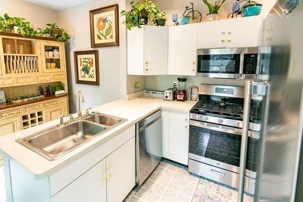 117 Church St Unit 4, North Attleboro, MA 02760 - kitchen with a sink, light countertops, a peninsula, stainless steel appliances, and white cabinetry