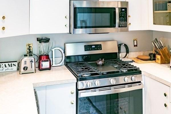 117 Church St Unit 4, North Attleboro, MA 02760 - kitchen with light countertops, white cabinetry, appliances with stainless steel finishes, and glass insert cabinets
