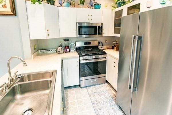 117 Church St Unit 4, North Attleboro, MA 02760 - kitchen featuring appliances with stainless steel finishes, a sink, light countertops, white cabinets, and glass insert cabinets