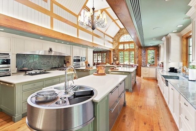 kitchen with green cabinetry, an island with sink, and white cabinets