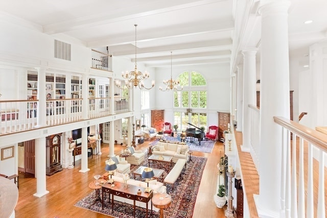 interior space with an inviting chandelier, light hardwood / wood-style flooring, beam ceiling, and decorative columns