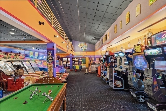 rec room with a drop ceiling and dark colored carpet