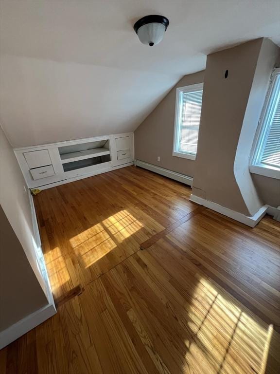 additional living space with light hardwood / wood-style flooring, a baseboard radiator, and lofted ceiling