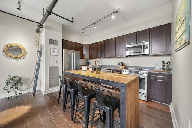 kitchen featuring dark brown cabinetry, appliances with stainless steel finishes, wooden counters, and dark hardwood / wood-style flooring