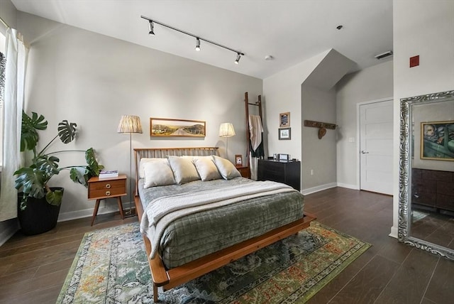 bedroom featuring lofted ceiling, dark wood-type flooring, and rail lighting