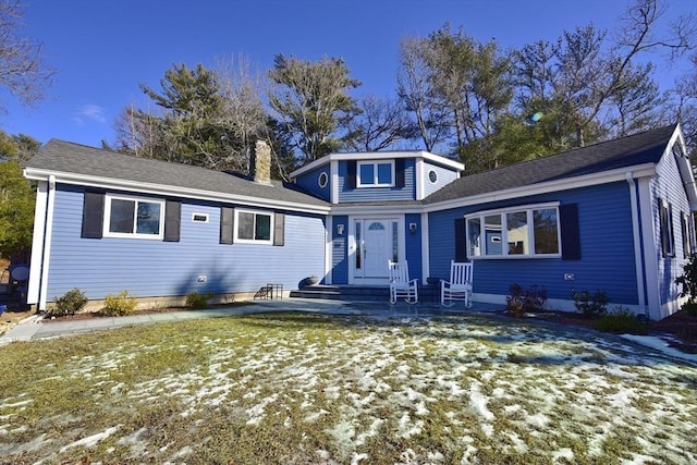 view of front of house with entry steps, a chimney, and a yard