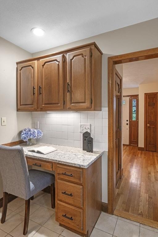 5 Ledgewood Rd, Saugus, MA 01906 - kitchen with light stone countertops, decorative backsplash, brown cabinetry, light tile patterned floors, and a desk