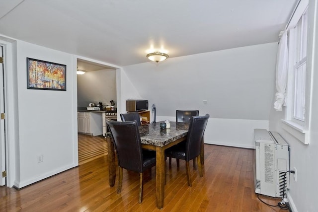 dining area with baseboards, heating unit, and wood-type flooring