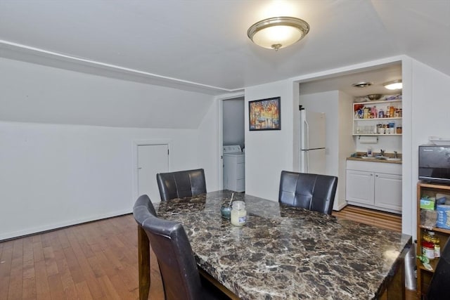 dining space with washer / dryer, lofted ceiling, and wood finished floors
