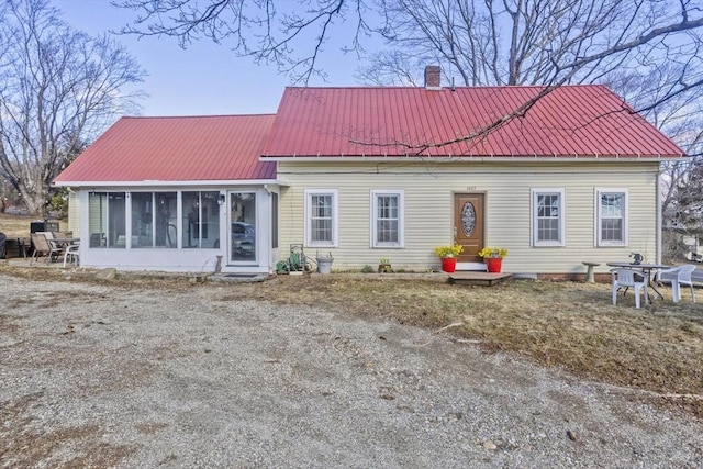 rear view of house with a chimney, a sunroom, and metal roof