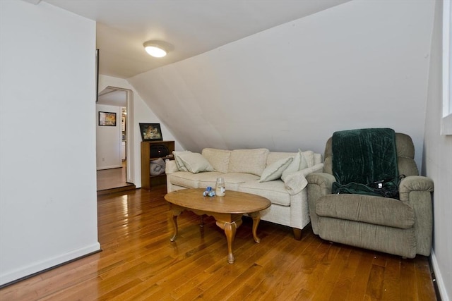 living area with hardwood / wood-style floors, lofted ceiling, and baseboards