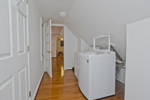 laundry area with laundry area, washer and clothes dryer, baseboards, and light wood finished floors