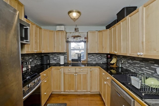 kitchen featuring light wood finished floors, stainless steel appliances, dark countertops, backsplash, and light brown cabinetry
