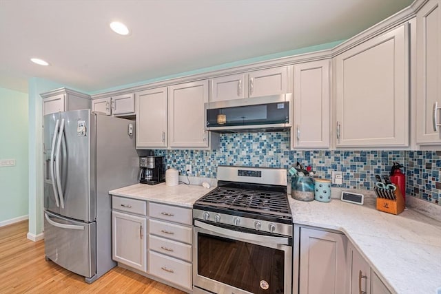 61 Hingham Ave, Marshfield, MA 02050 - kitchen with stainless steel appliances, backsplash, light wood-type flooring, light stone countertops, and recessed lighting
