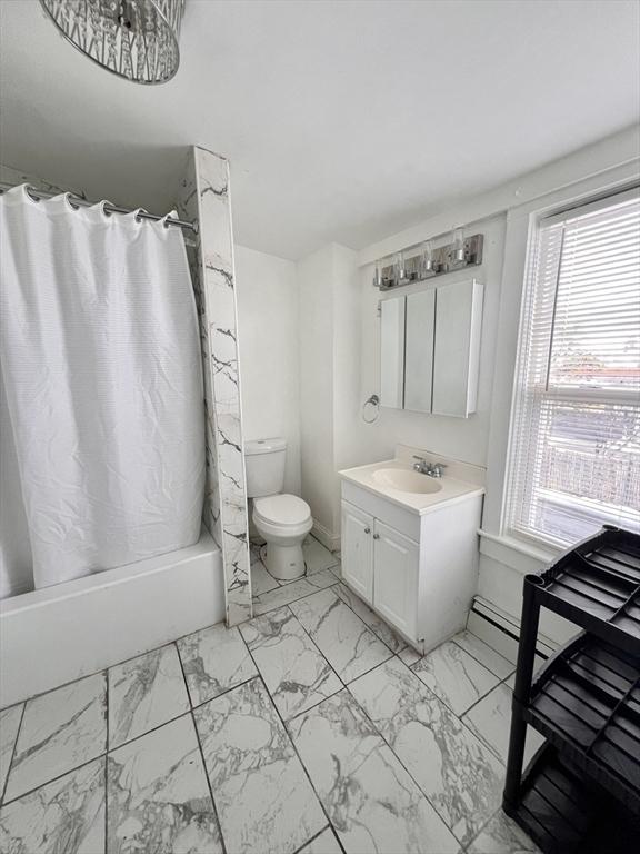 full bath featuring marble finish floor, shower / tub combo with curtain, vanity, and toilet