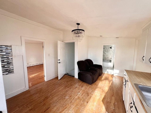 sitting room with a baseboard heating unit, a chandelier, and light wood-style flooring