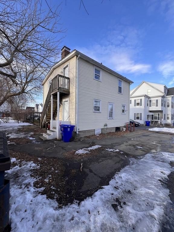 view of snow covered exterior featuring a residential view, a chimney, and a balcony