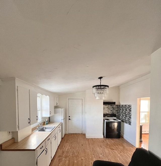 kitchen with a sink, white cabinetry, electric stove, light countertops, and decorative light fixtures