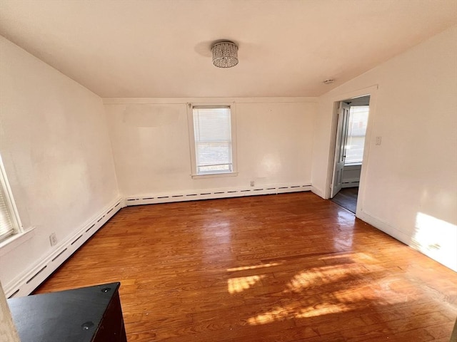 spare room featuring a baseboard heating unit and wood finished floors