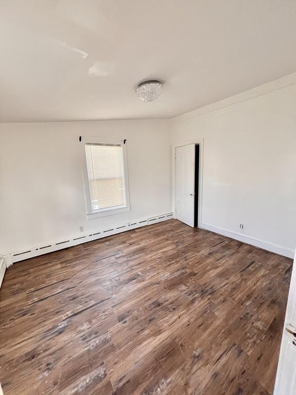 spare room featuring dark wood-style floors and a baseboard radiator