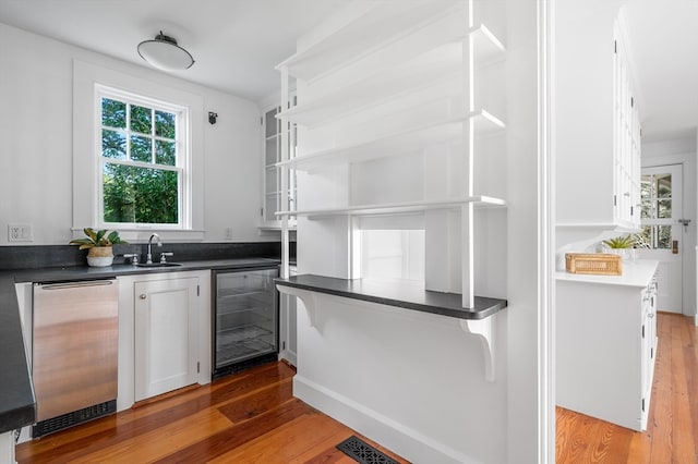 kitchen featuring white cabinets, hardwood / wood-style flooring, sink, and beverage cooler