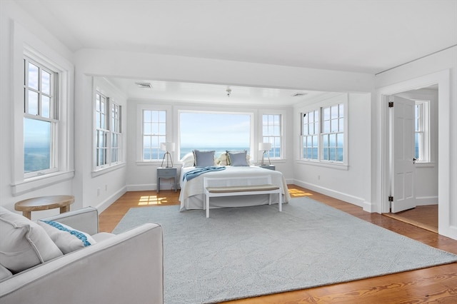 bedroom with multiple windows and light hardwood / wood-style flooring