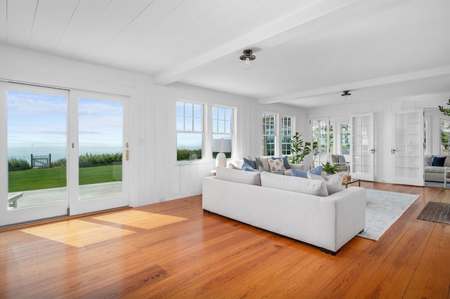 living room with french doors, beam ceiling, light hardwood / wood-style floors, and a healthy amount of sunlight