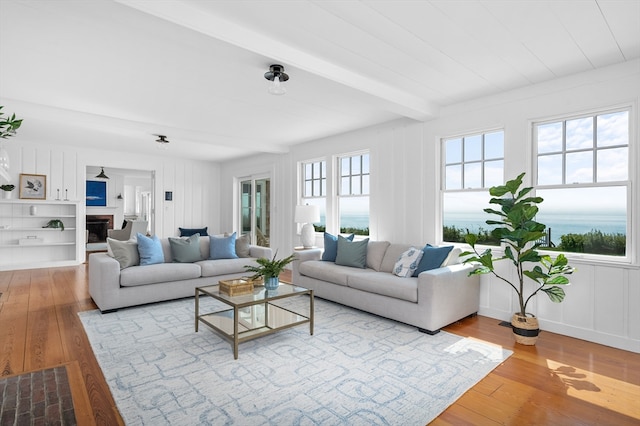 living room with hardwood / wood-style flooring, beam ceiling, and a water view