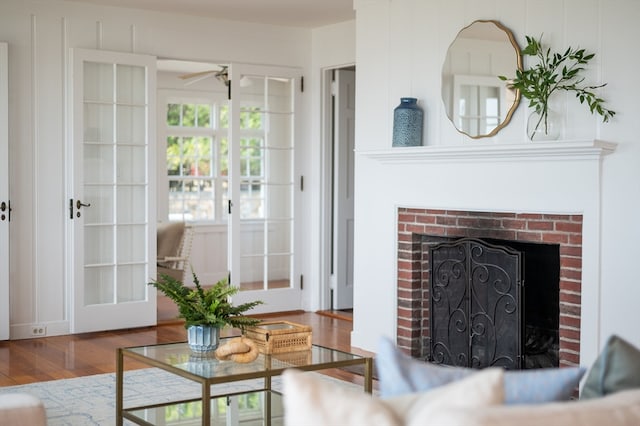 living room with a brick fireplace, ceiling fan, and hardwood / wood-style floors