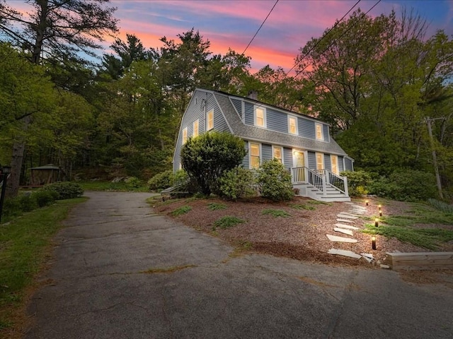 colonial inspired home featuring a gambrel roof, driveway, and a shingled roof