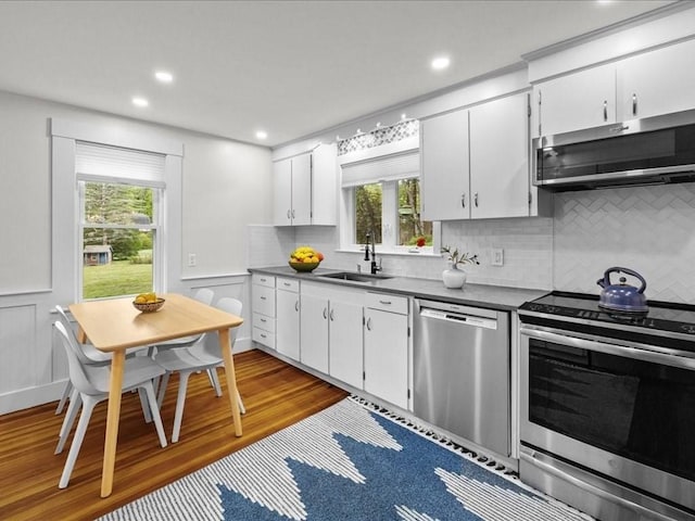kitchen featuring stainless steel appliances, a sink, dark countertops, tasteful backsplash, and recessed lighting