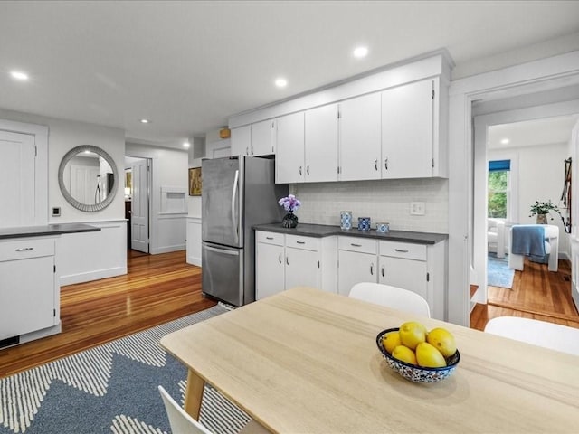 kitchen with freestanding refrigerator, wood finished floors, dark countertops, white cabinetry, and recessed lighting