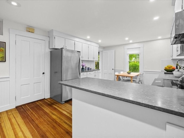 kitchen with freestanding refrigerator, dark wood finished floors, white cabinetry, ventilation hood, and dark countertops