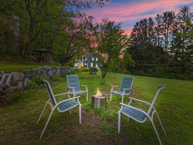 yard at dusk with an outdoor fire pit and a yard