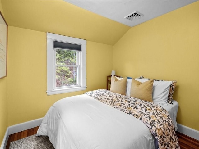 bedroom featuring baseboards, wood finished floors, and lofted ceiling