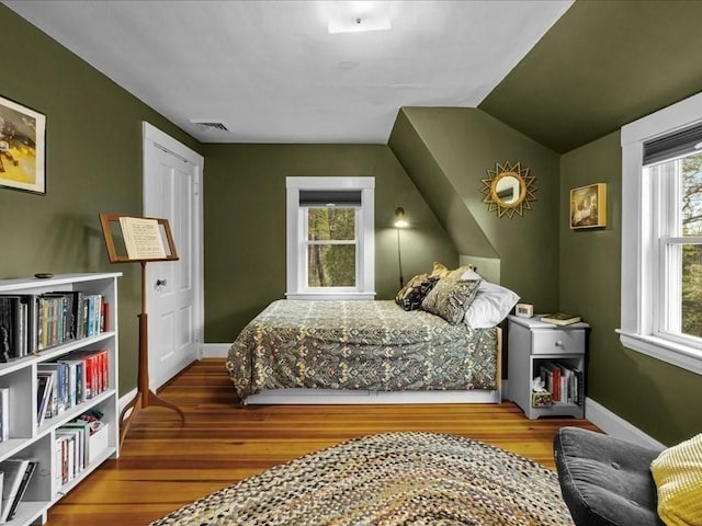 bedroom featuring wood finished floors, baseboards, and vaulted ceiling