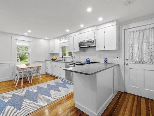 kitchen featuring stainless steel appliances, hardwood / wood-style floors, healthy amount of natural light, white cabinets, and recessed lighting