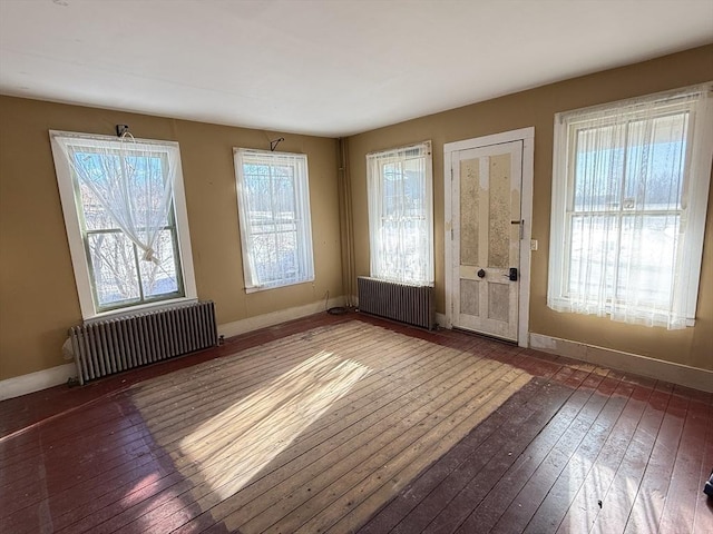 doorway with radiator heating unit, dark hardwood / wood-style floors, and a healthy amount of sunlight