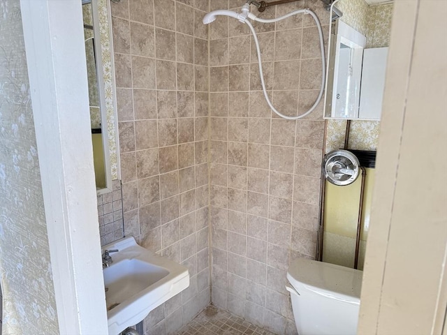 bathroom with toilet, sink, tile walls, and a tile shower