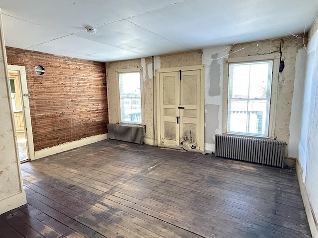 unfurnished room with dark hardwood / wood-style flooring and radiator