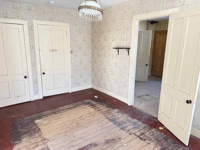 spare room featuring a notable chandelier and dark hardwood / wood-style floors