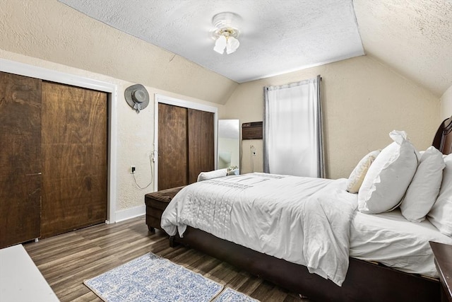 bedroom with a textured ceiling, lofted ceiling, wood finished floors, and baseboards