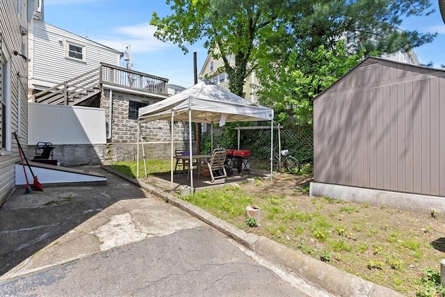 view of yard featuring a patio area, fence, an outbuilding, and a shed
